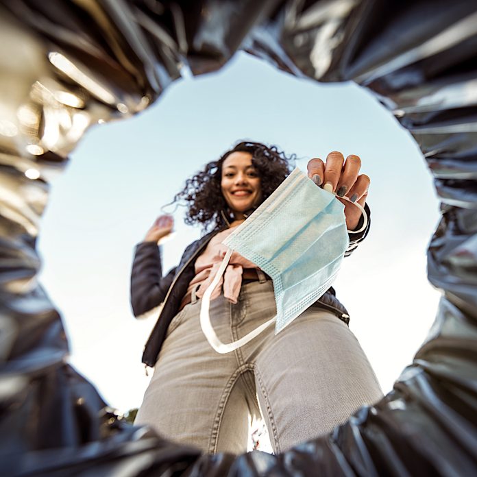Woman throwing used protective surgical mask into the garbage bin from inside